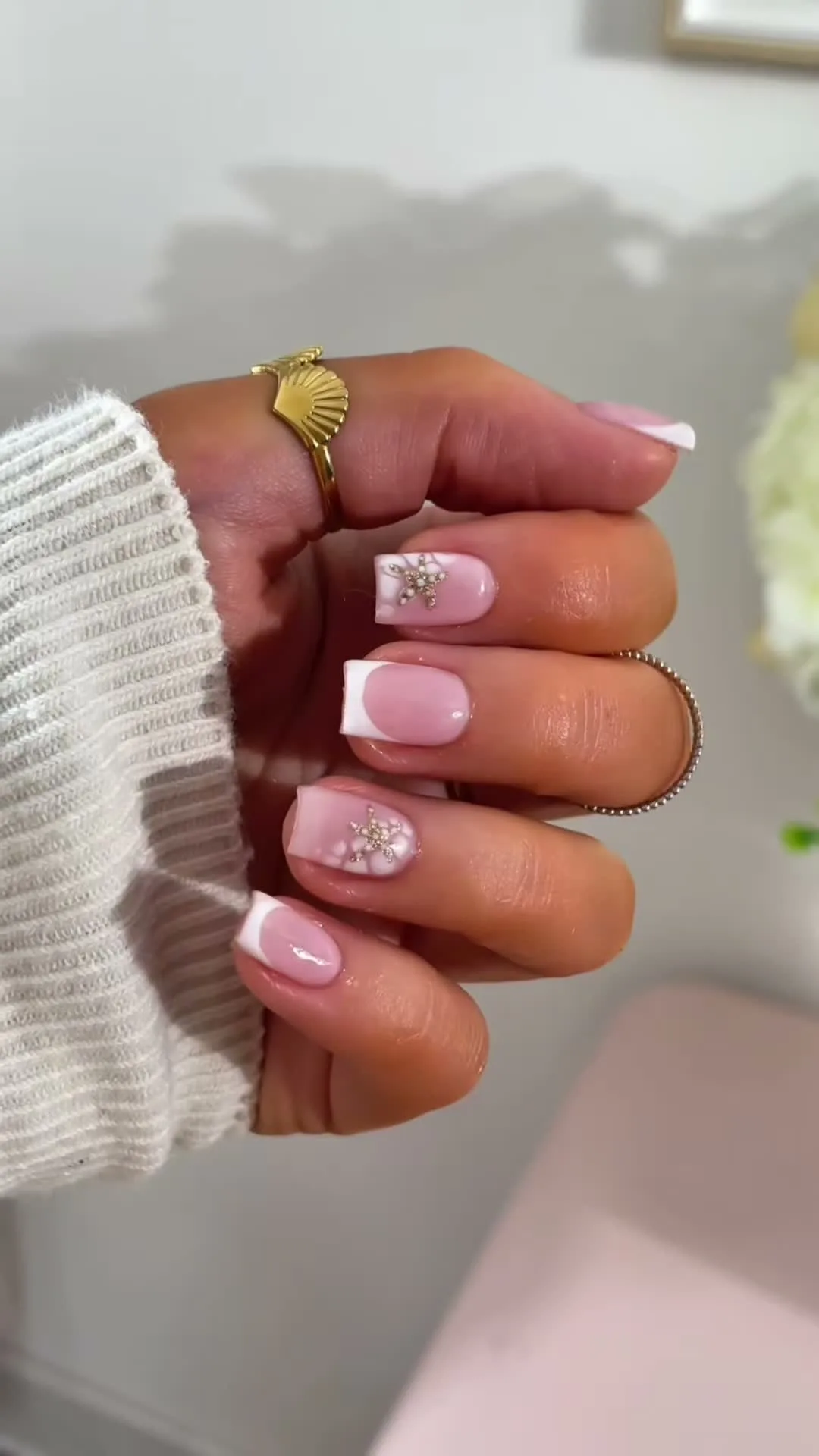 Milky white French tips with tiny florals and a gold starfish accent